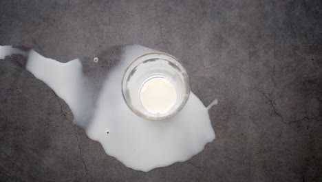 spilled milk and an empty glass on a dark surface