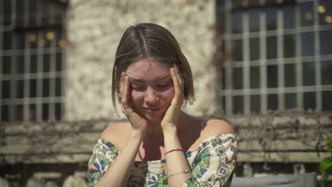 Close-up-shot-of-depressed-and-disappointed-woman-holding-head-outdoors-in-sunlight