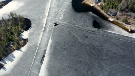 pan up of melting ice road running through the middle of a lake in northern canada