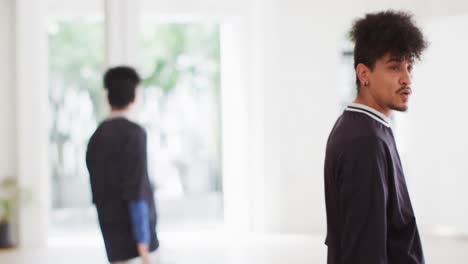 bailarín masculino biracial bailando solo frente al espejo en un estudio de baile, cámara lenta