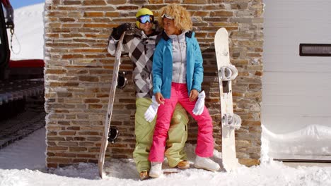 close couple posing with snowboards against garage