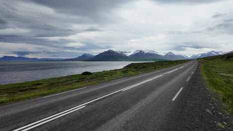 Dynamic footage showcasing two cyclists pedaling along Road 82 near Dalvik, Iceland, backdrop of northern Iceland's breathtaking coastal and mountain scenery.