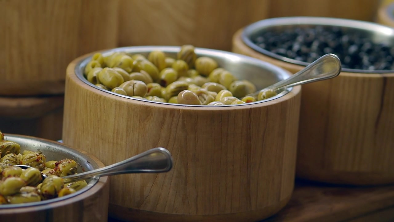 Olive fresche verdi e nere esposte in ciotole di legno