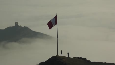 two hikers reaching the top of mountain above the clouds