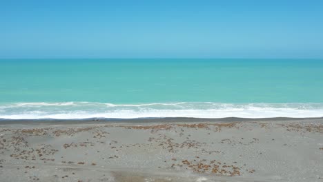 descending to reveal barren beach features in contrast to beautiful colors of ocean and sky