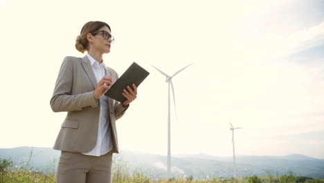 visão inferior da engenheira caucasiana usando um tablet na estação eólica de energia renovável