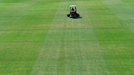 imágenes de 4k: un personal en un vehículo para cortar césped prepara un campo deportivo en un día soleado de verano en dubai, emiratos árabes unidos