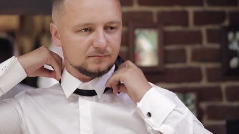 groom adjusts bow tie, preparing to go to the bride, businessman in white shirt, wedding day