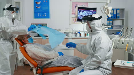 assistant in protective equipment putting dental bib to patient