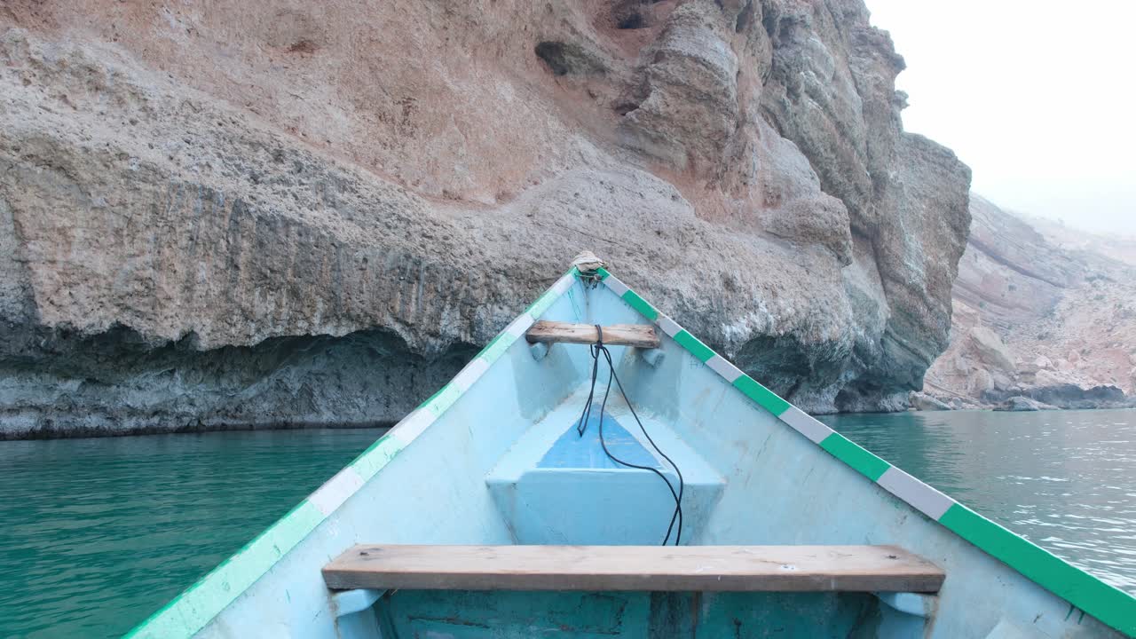 Prospettiva da una barca che naviga in mare vicino a una formazione rocciosa a picco sull'Isola di Socotra, Yemen