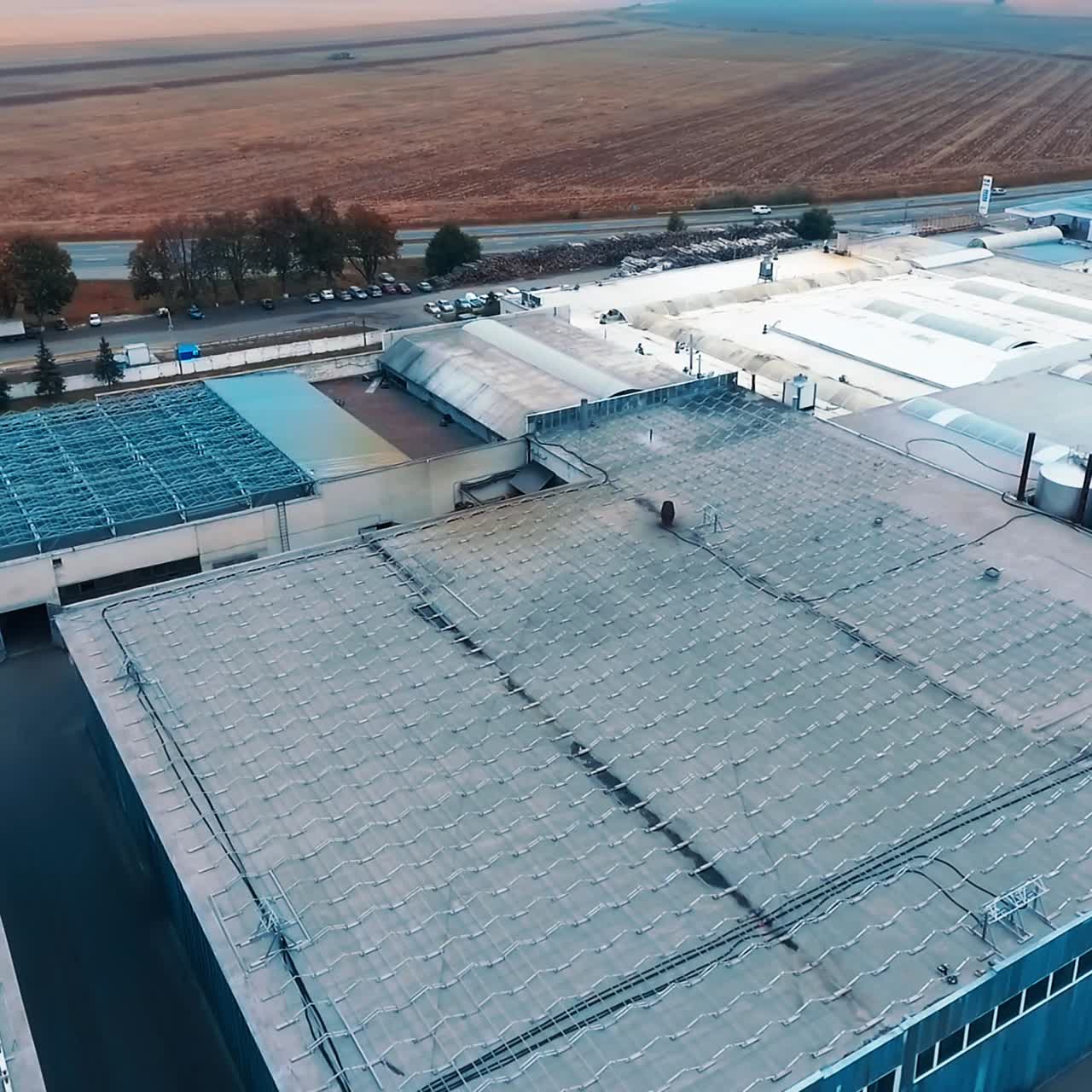 Storehouses with metal constructions on top. Storage premises at suburban area with country houses and farmlands. Circe movement. Top view