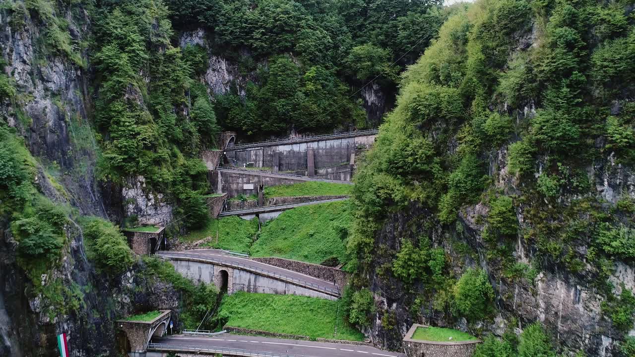 Curving alpine road cuts through steep cliffs of San Boldo Pass under cloudy sky