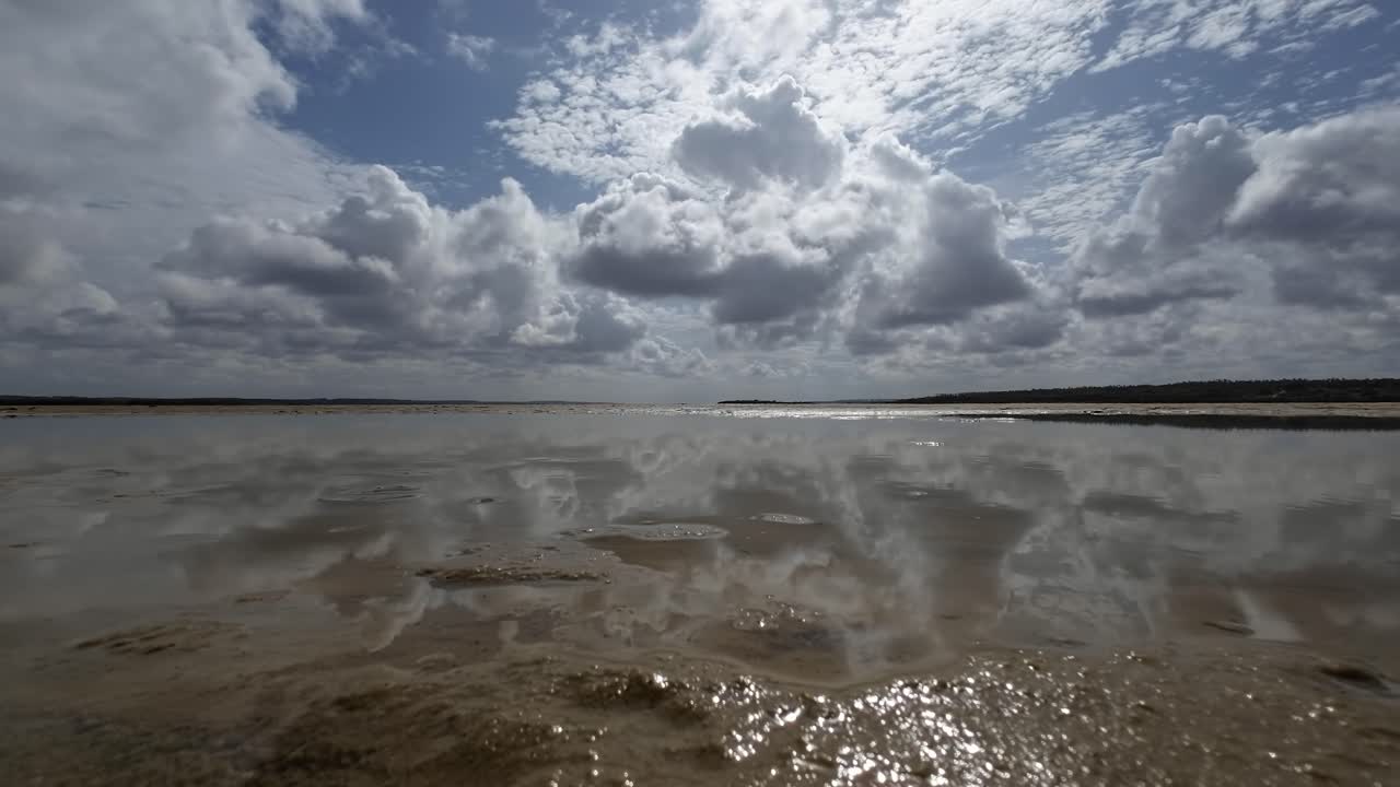 Beautiful trucking right landscape worms eye view shot of a tropical wet sand bar in the Guara&iacute;ras Lagoon of Tibau do Sul, Brazil in Rio Grande do Norte during a sunny summer cloudy day near Pipa
