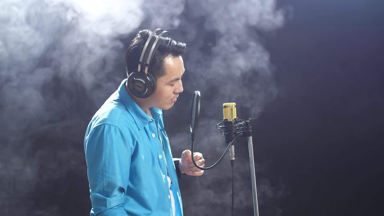 연기가 가득 찬 스튜디오 에서 마이크 로 노래 하는 남자