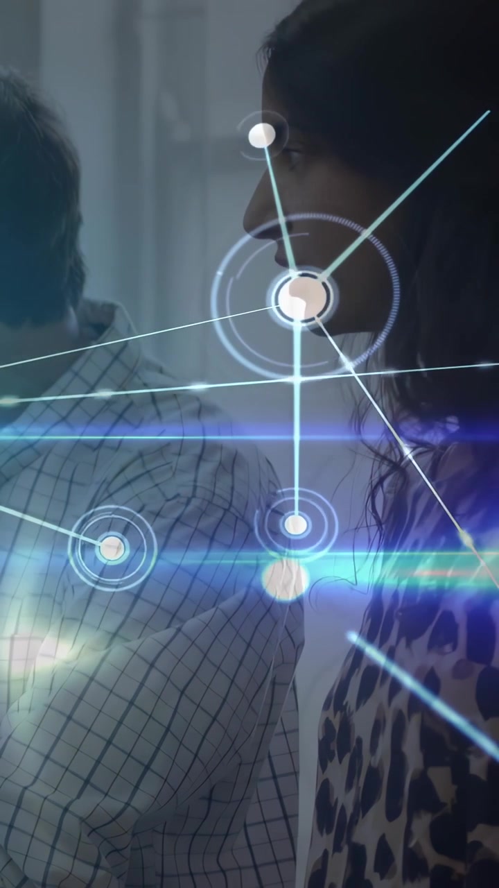 Vertical video: Woman pointing pen at laptop, man listening, forming HUD network for tech planning