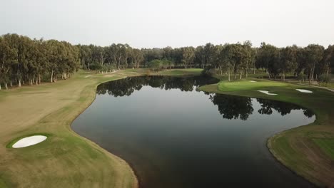 Riesiger-Teich-Mit-Blauem-Wasser-In-Der-Mitte-Des-Golfplatzfeldes-In-Luftaufnahme