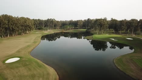 estanque de agua azul masivo en medio del campo de golf en tiro aéreo