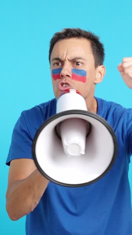 excited man with haitian flag on face using a megaphone
