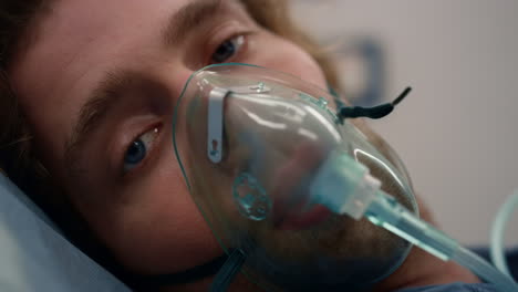 Closeup-ill-man-in-oxygen-mask-lying-on-stretchers-in-emergency-car