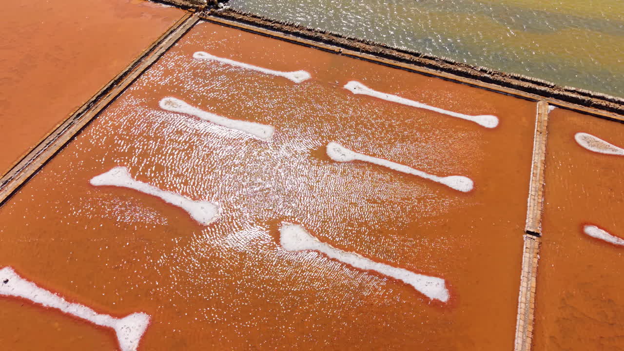 Stunning drone view of orange salt pans in Sicily, Italy, white salt lines and colorful water pools