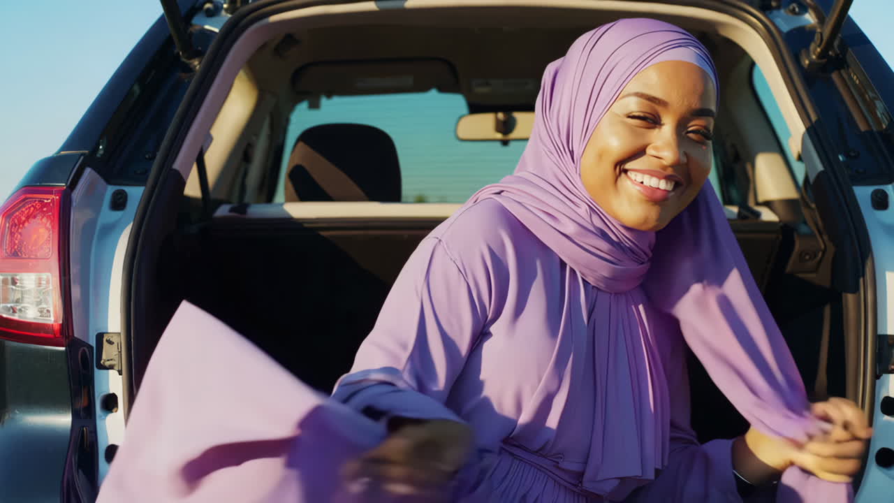 Joyful Muslim Woman in Purple Hijab in Car Trunk