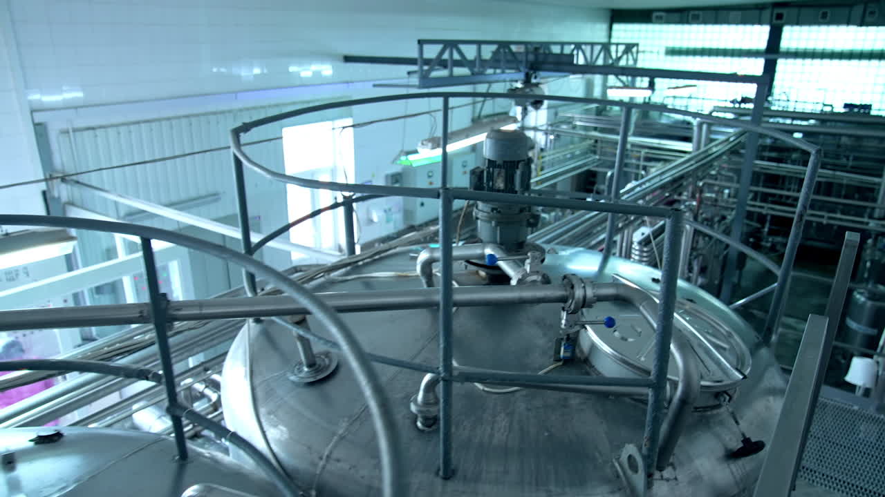Tops of enormous steel tanks. Metal reservoirs risen above the other technological devices. Large windows at the backdrop.