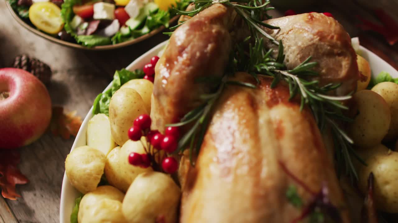 Video di vassoio con tacchino arrosto, diverse pietanze e decorazione autunnale su superficie di legno