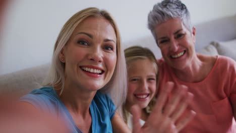 Abuela-Caucásica,-Madre-E-Hija-Saludando-Mientras-Hacen-Una-Videollamada-En-Un-Teléfono-Inteligente-En-Casa