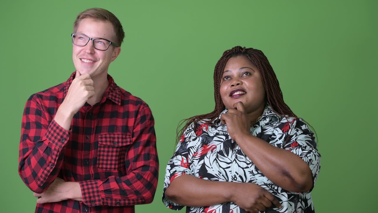 mujer africana con sobrepeso y un joven escandinavo juntos contra un fondo verde
