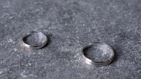 Silver-wedding-rings-on-marble-desk-with-engraved-names-and-date