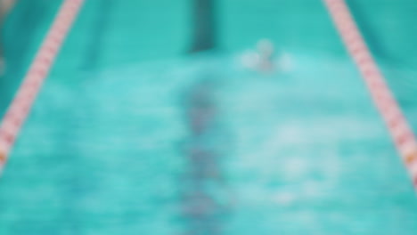 blurred out of focus shot of professional swimmer athlete swimming in pool