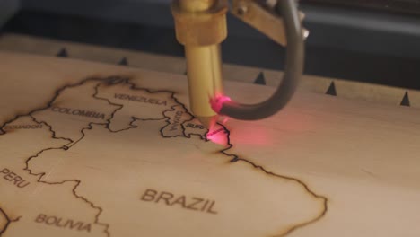 cnc laser cutting machine cuts world map on wooden plank and plywood