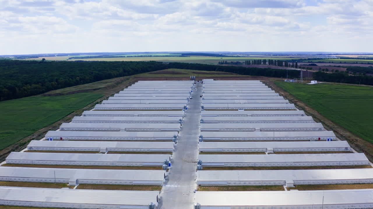 Farm buildings on nature landscape. White warehouses on green field in the countryside. Modern agriculture. Aerial view.