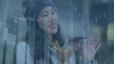Animation-of-multiple-graphs-with-numbers-over-smiling-asian-woman-talking-on-cellphone