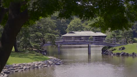 teahouse in the famous hamarikyu gardens in tokyo in distance with wooden bridge in front