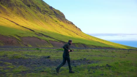 caucasian man running on grassy terrain near the mountains of seljavallalaug in southern iceland