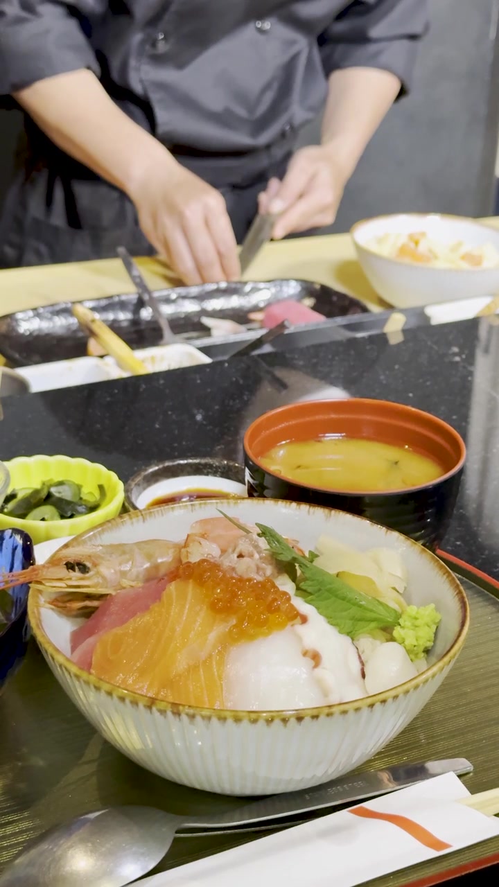 日本料理店のカウンターで、プロのシェフが色鮮やかな海鮮丼を準備する様子を固定カメラでクローズアップ撮影。
