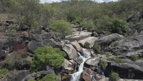 aerial shot of the waterfall of davies creek falling over the rocks in the far north region of queensland, australia - drone