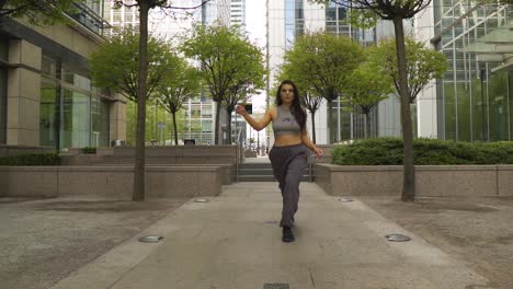 very confident female urban street dancer cat walking towards the camera with attitude dominating her space face expressions on point slow motion high towers park metropolis