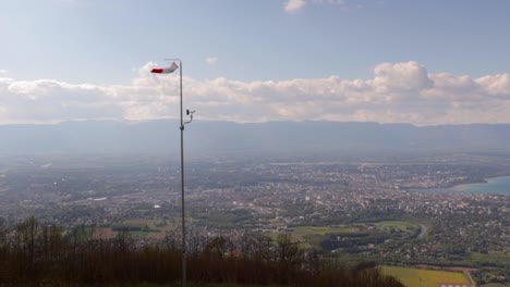 manga de viento volando en la cima de una montaña con ginebra detrás en el valle con nubes en un día soleado, todavía tiro de gran angular