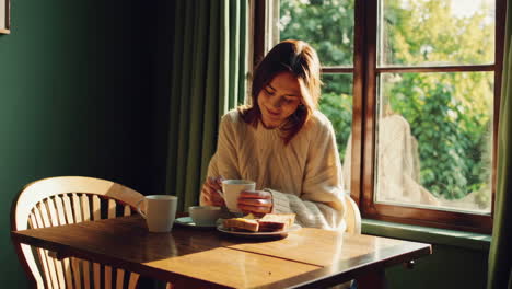 woman enjoying coffee and breakfast by the window