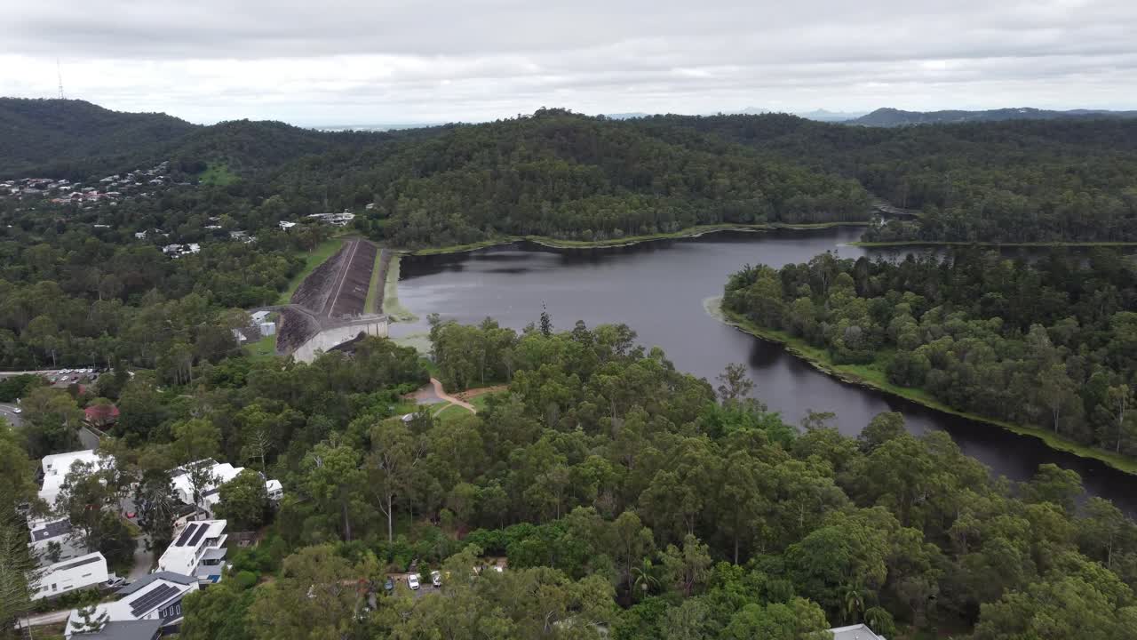drone volando hacia un embalse de agua en australia mostrando una pared de presa y el matorral verde alrededor del lago