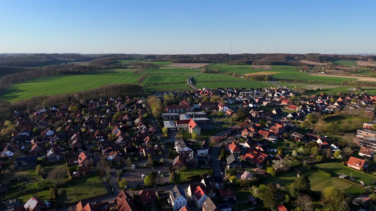 Historic School in small american town with farm fields in background. Aerial forward wide shot. Red brick houses and homes in American neighborhood. Sunset time in USA. Spring day with blue sky.