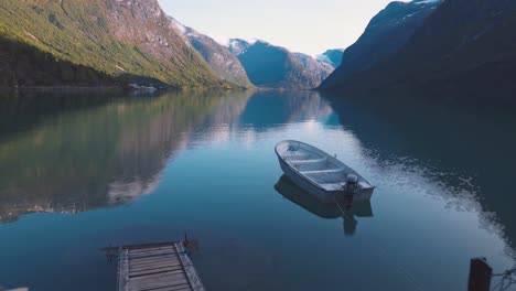 Vista-Panorámica-De-Un-Pequeño-Bote-Tendido-En-El-Muelle-De-Un-Gran-Lago,-Rodeado-De-Montañas-En-Noruega,-Lovatnet