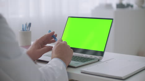 el médico está dando una conferencia médica en línea en primer plano en una computadora portátil con pantalla verde para la tecnología de llave de croma en la mesa
