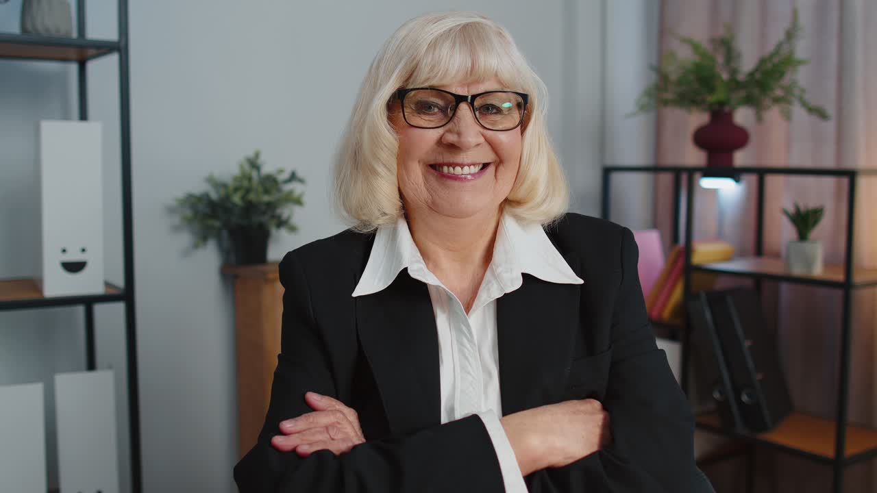 Cheerful senior mature business office woman wears glasses formal suit smiling looking at camera