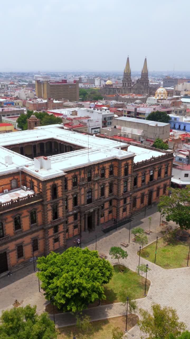 Slow pan left overlooking Ministry of Culture building facade in Guadalajara, with the iconic Guadalajara Cathedral in the background