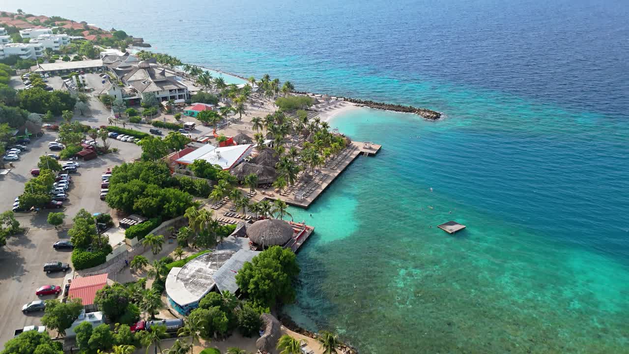 Drone in ascesa sopra acque caraibiche limpide color turchese presso le spiagge di Jan Thiel e Zanzibar, Curaçao