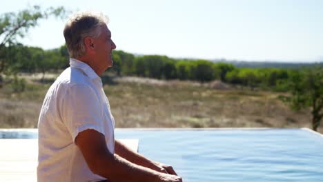 Thoughtful-man-sitting-near-pool-side-4k