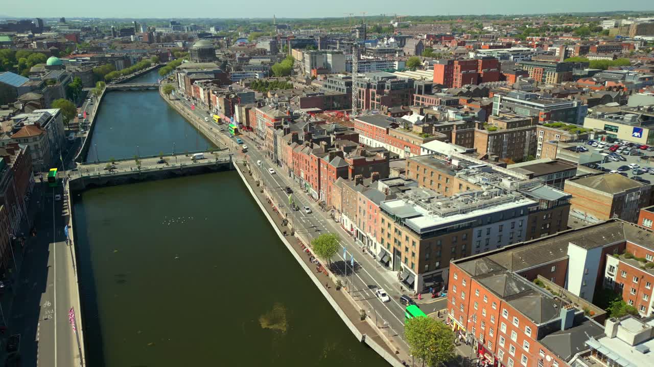 Wide, forward travelling erial video of the River Liffey, and the Ha'penny Bridge in Dublin City Centre, Ireland on a bright and sunny day. Filmed in 4K, 60FPS and with Rec709 color.